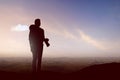 Silhouette of a man with a backpack holding the camera on the top of the hills Royalty Free Stock Photo