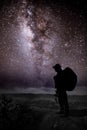 Silhouette of man with backpack and trekking poles against amazing Milky Way at night. Photographer and star in the night sky. Royalty Free Stock Photo