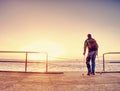 Silhouette of man with backpack on the pier on the calm sea