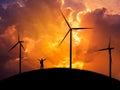 Silhouette the man backpacker standing raised up arms celebrate with wind turbines generating electricity in sunset. Royalty Free Stock Photo