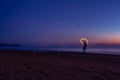 Silhouette of man on the beach making sparks with steel wool. Long exposure light painting photography. Light shapes on the beach Royalty Free Stock Photo