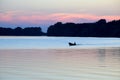 Silhouette of a man in a boat that floats in the river at sunset Royalty Free Stock Photo