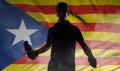 Silhouette of a man with a burning bottle on the background of the flag of Catalonia