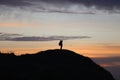 silhouette of a man in a cap sitting on a mountain watching the sunset. Royalty Free Stock Photo