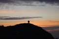 silhouette of a man in a cap sitting on a mountain watching the sunset. Royalty Free Stock Photo