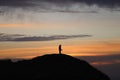 silhouette of a man in a cap sitting on a mountain watching the sunset. Royalty Free Stock Photo