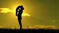 Silhouette of man and child on sunset background. The father holds the son of his son`s son and kisses him at a slow