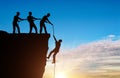 Silhouette of a man climbers pulling out of a cliff of another climber