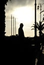 Silhouette of a man in a coat and hat on sea coast at sunset. Mystery or solitude concept. Suitable for a cover of a thriller book Royalty Free Stock Photo