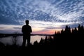 Silhouette of a man controlling a drone that is in the background with the sun setting over downtown Vancouver.