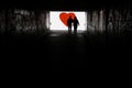 Silhouette of a man in a dark tonel against a background of a large red heart. Love, loneliness, conceptual photo.