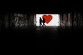 Silhouette of a man in a dark tonel against a background of a large red heart. Love, loneliness, conceptual photo.