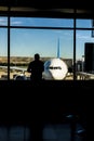 Silhouette of a man in the departure lounge look at plane