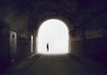 Silhouette of a man disappearing into the light at the end of a tunnel.