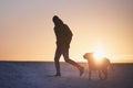 Silhouette of man with dog on snowy meadow Royalty Free Stock Photo