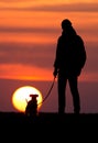 Silhouette of man with dog at sunset Royalty Free Stock Photo