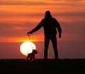 Silhouette of man with dog at sunset Royalty Free Stock Photo