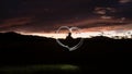 Silhouette of a man draws a heart shape with a flashlight through the air Royalty Free Stock Photo