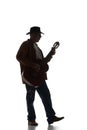 Silhouette of man in fedora hat playing guitar, performing isolated on white background. Black and white image. Royalty Free Stock Photo