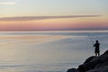 Silhouette of man with fishing spinning. Fishing on the lake at beautiful sunset. Lake Ontario. Rochester, USA