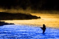 Silhouette of Man Flyfishing Fishing in River Golden Sunlight and Cool Blue Water