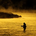 Silhouette of Man Flyfishing Fishing in River Golden Sunlight Royalty Free Stock Photo