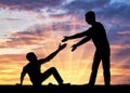 Silhouette of a man giving a helping hand to another man who fell to the ground Royalty Free Stock Photo