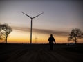 Silhouette of a man goes to sunset in the direction of wind turbines Royalty Free Stock Photo