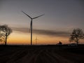 Silhouette of a man goes to sunset in the direction of wind turbines Royalty Free Stock Photo