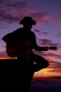 Silhouette of man with guitar sit by water sunset Royalty Free Stock Photo