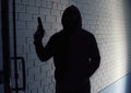 Silhouette of man with gun in hoodie. Dangerous criminal