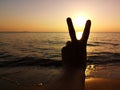 Silhouette of man hand hold V-sign at the beach while the sunset. Refresh for tommorow. Goal and hope concept Royalty Free Stock Photo