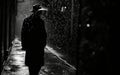 Silhouette of a man in a hat in a dark, rainy urban alleyway. Royalty Free Stock Photo