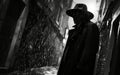 Silhouette of a man in a hat in a dark, rainy urban alleyway. Royalty Free Stock Photo