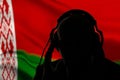 Silhouette of a man in headphones, secret agent eavesdropping, spy and intelligence officer, Belarusian flag, lighting Royalty Free Stock Photo