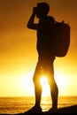 Silhouette, man and hiking at ocean with sunset, backpack and scenery for holiday or vacation is summer. Shadow, person