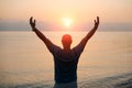 Silhouette man with his hands raised at sunset on beach arms out to sides Royalty Free Stock Photo