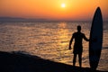 Happy surfer standing with surfboards on the beach, at sunset. Royalty Free Stock Photo