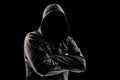 Silhouette of a man in a hood on a black background, his face is not visible, he folded his arms over his chest. The concept of a Royalty Free Stock Photo