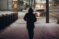 Silhouette of a man in the hood that walks down the street at night in the snowfall Royalty Free Stock Photo