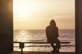 Silhouette of a man in a hooded jacket sitting on a bench and wa Royalty Free Stock Photo