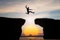 Silhouette of Man jump through the gap between hill on sunset background, business concept idea Royalty Free Stock Photo