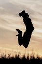 Silhouette of a man in a jump with his hands behind his head