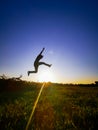 A silhouette man jump over the sun with his hand reach out at the sky