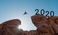 Silhouette a man jumping across cliff to 2020, New year 2020 and challenge concept