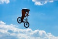 Silhouette of a man jumping on a Bicycle against a blue sky with white clouds. Royalty Free Stock Photo