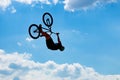 Silhouette of a man jumping on a Bicycle against a blue sky with white clouds.