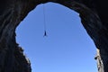 Silhouette of a man jumping in a cave hanging high on a cord