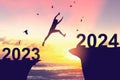 Silhouette man jumping between cliff with number 2022 to 2023 and birds flying at tropical sunset beach. Freedom challenge and Royalty Free Stock Photo