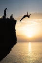 Silhouette of a man jumping off a cliff into the ocean at sunset Royalty Free Stock Photo